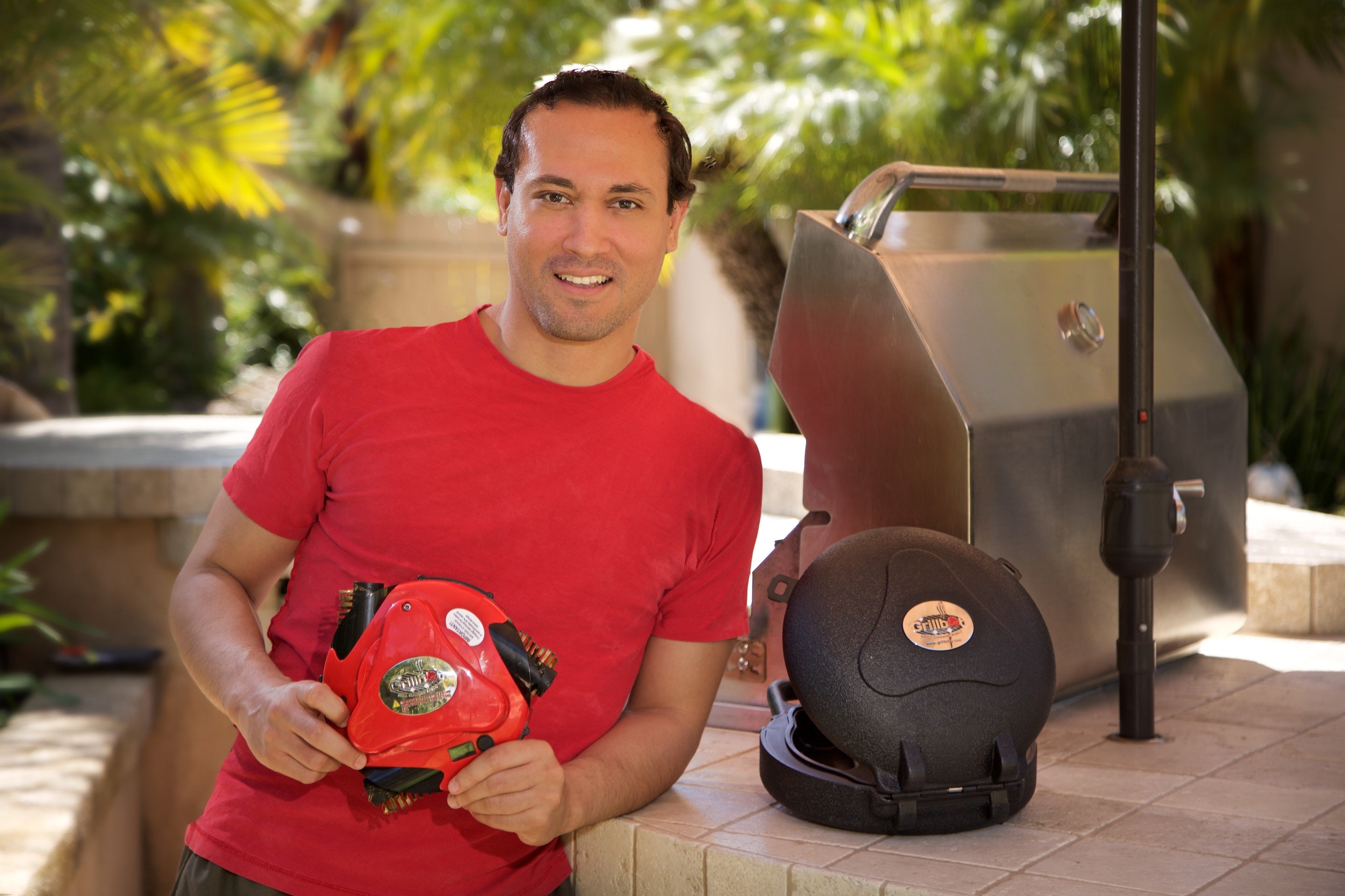 Man Holding Red Grillbot with Black Grillbot Case On Side 